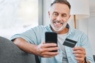 Foto: Mann mit Mobiltelefon und Kreditkarte